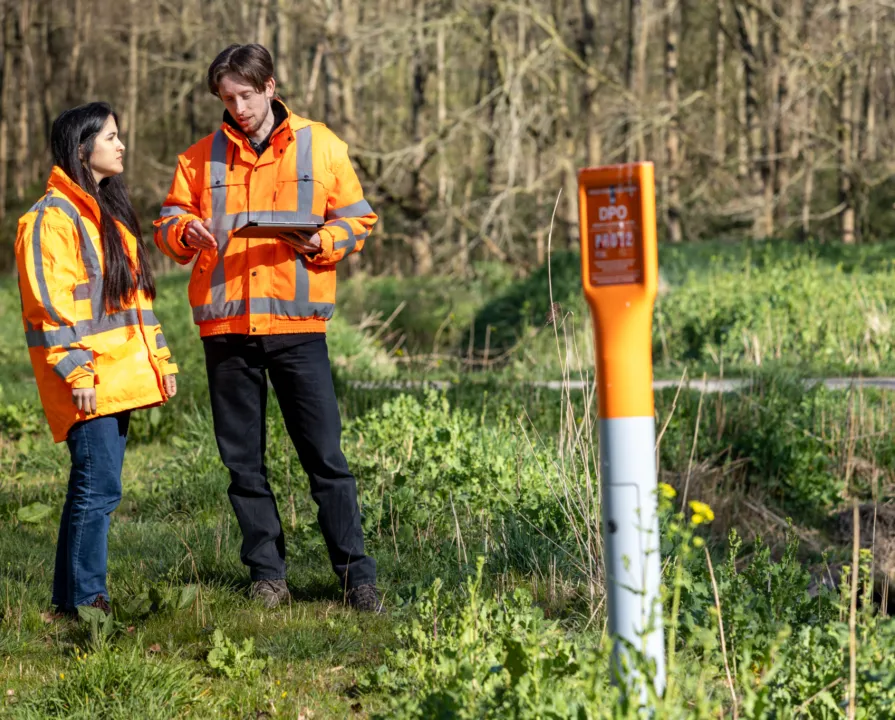 Two people using COSMIC-EYE, satellite technology, to protect critical underground infrastructure.